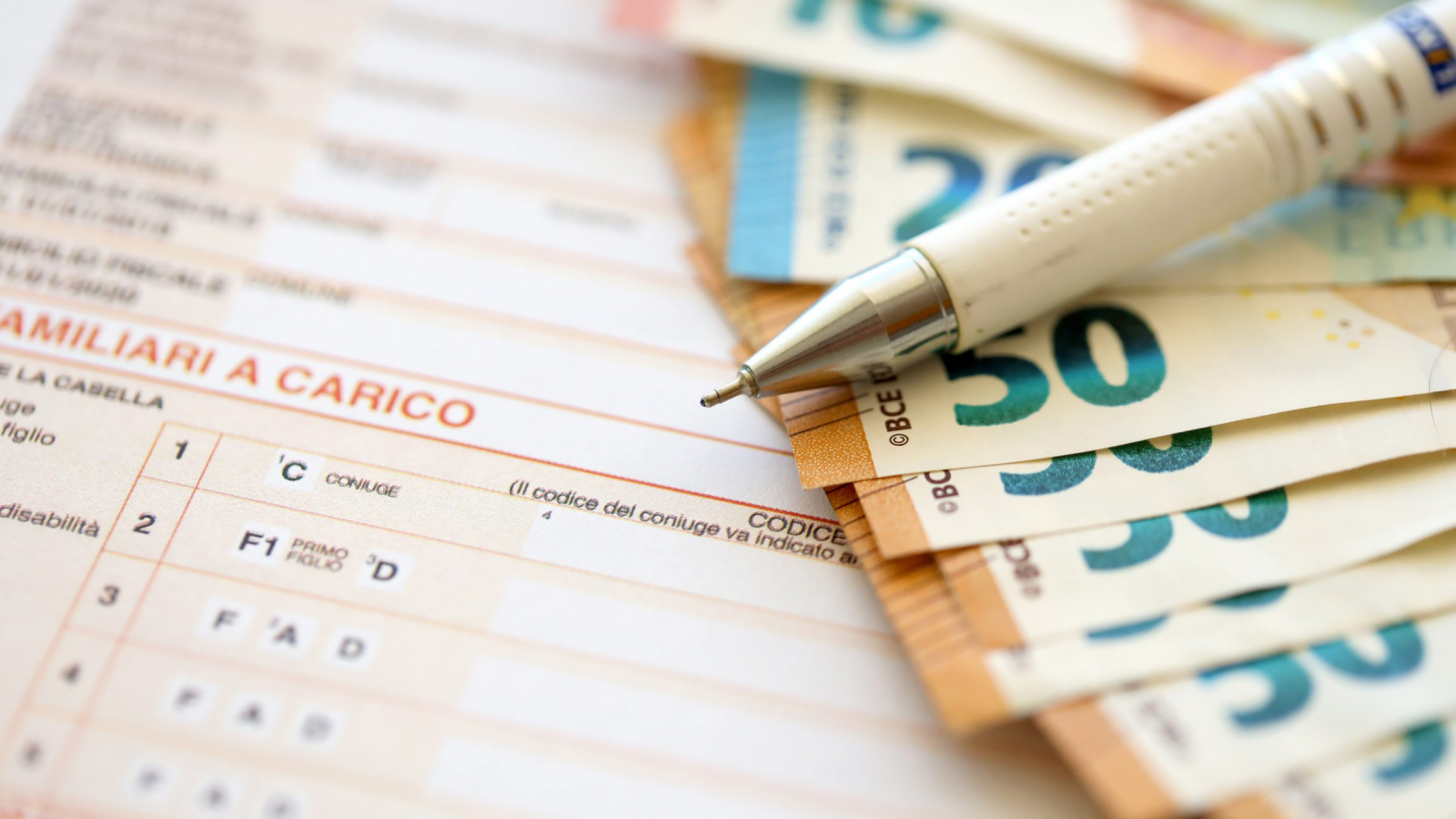 Filling italian tax form process with pen and euro money bills close up. Tax paying period and deadline